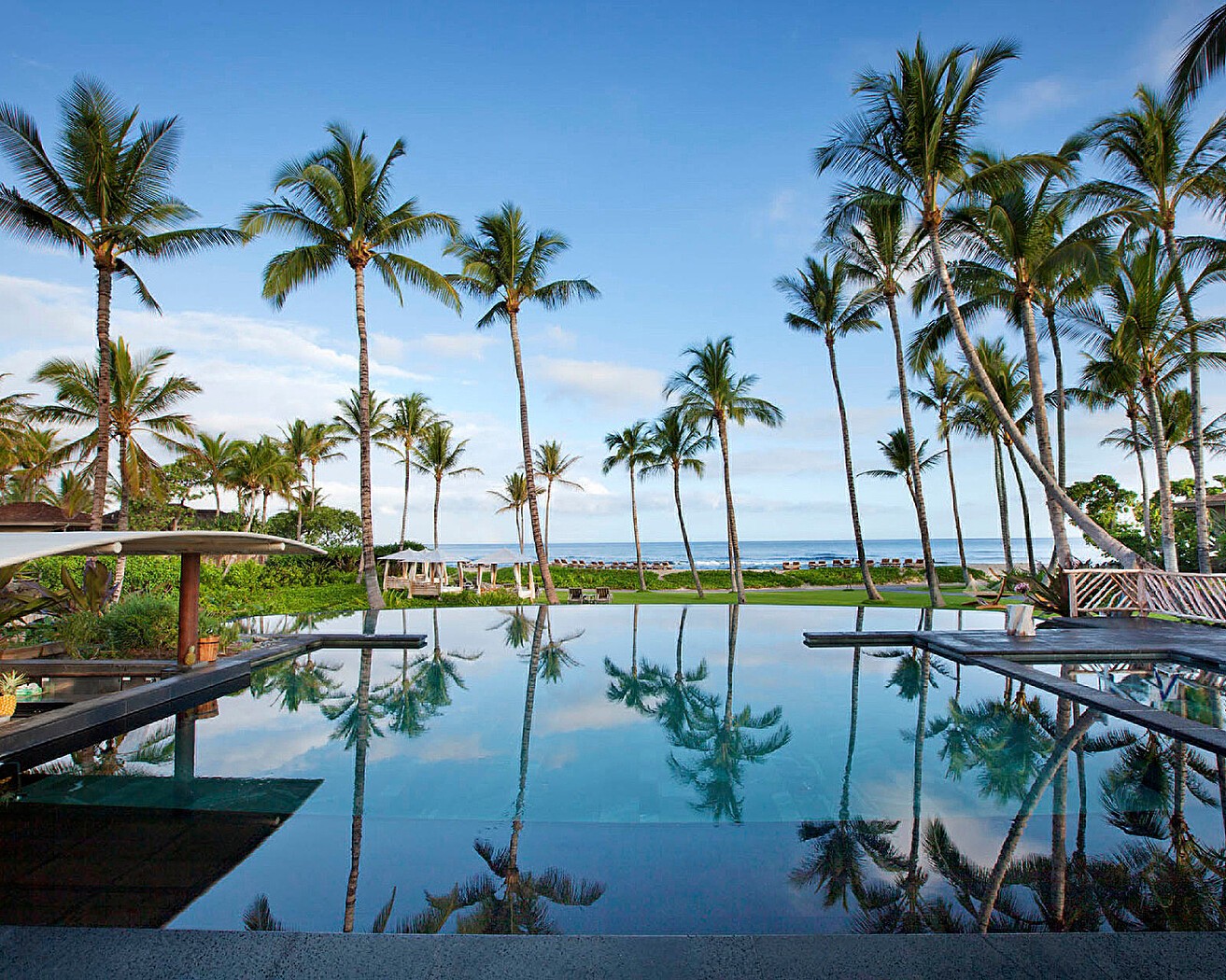 Infinity pool overlooking palm trees and the ocean at Four Seasons Resort Hualalai